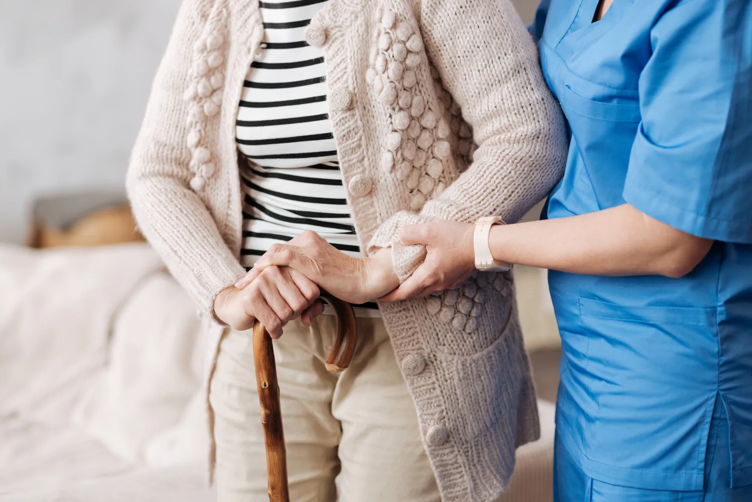 Sanfte, ausgebildete Krankenschwester hilft einer älteren Patientin